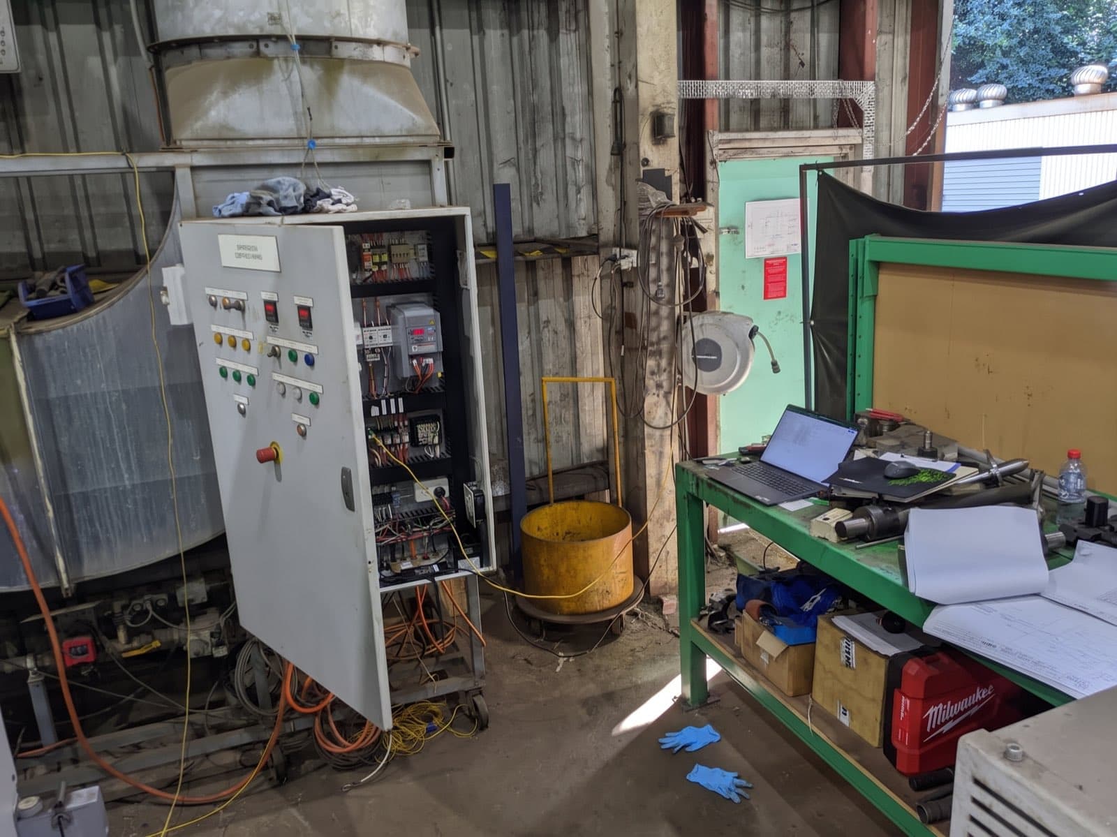 Open control panel and a laptop on the bench during fault finding on a plant floor